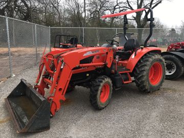 An orange tractor parked near a fence