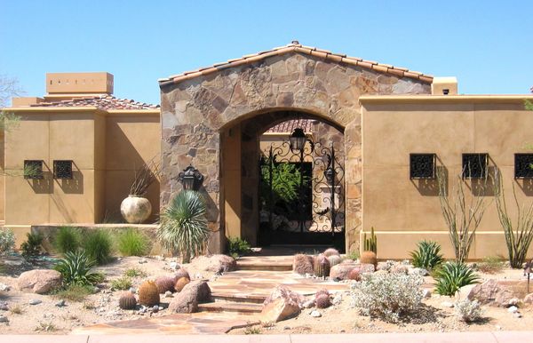 Desert-style house entrance with stone arch and cactus landscaping.