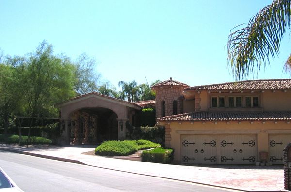 Luxury Mediterranean-style house with tiled roof and ornate garage doors.