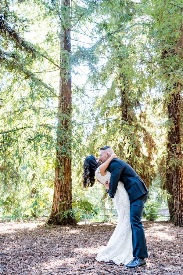 Wedding Photography. Picture of a couple kissing in a forest with tall trees. 