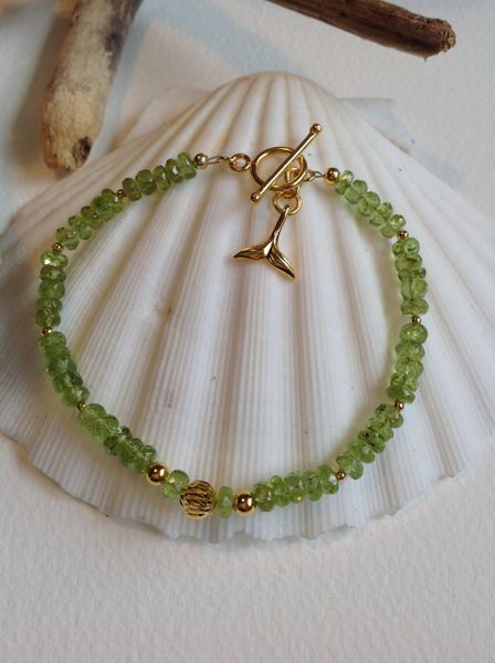 PERODOT AND GOLD BRACELET WITH 'WHALE FLUKE' CHARM.