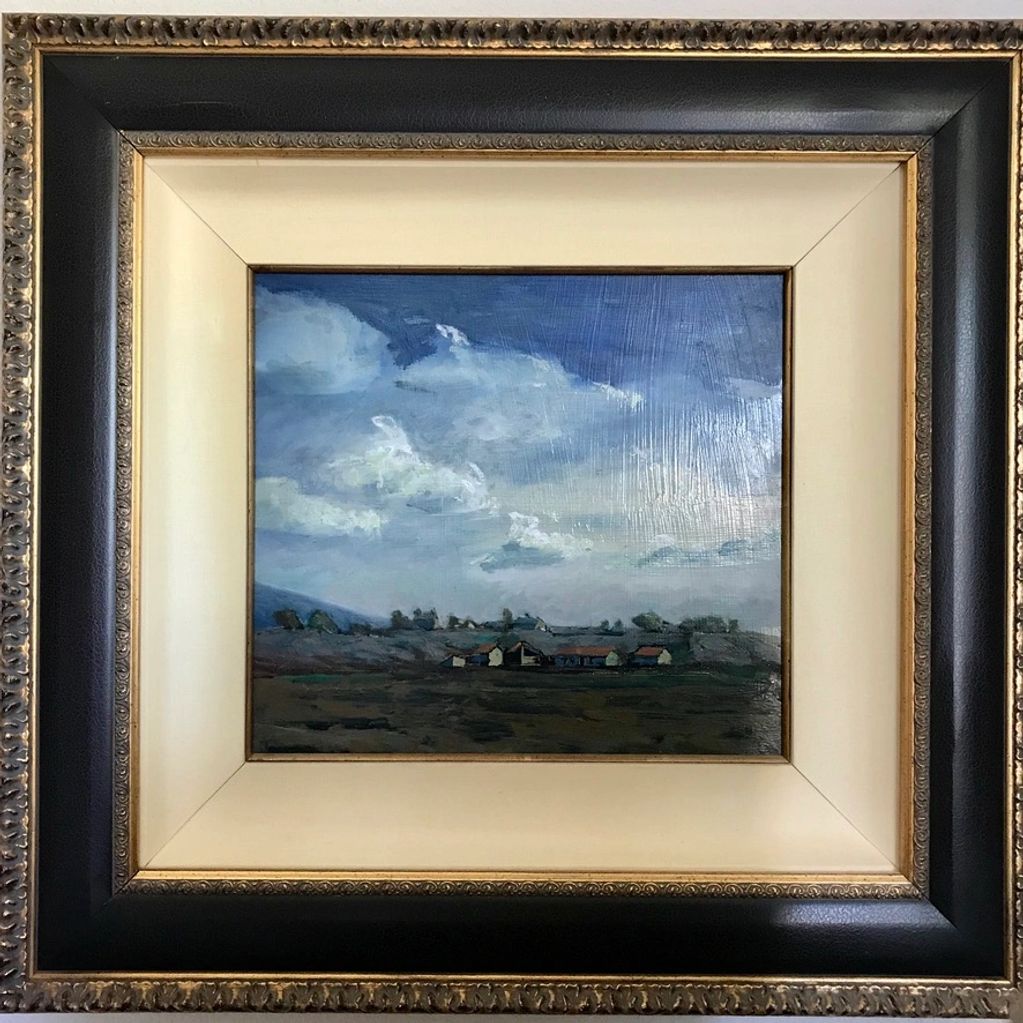 Framed painting of a cloudy sky over a rural landscape.