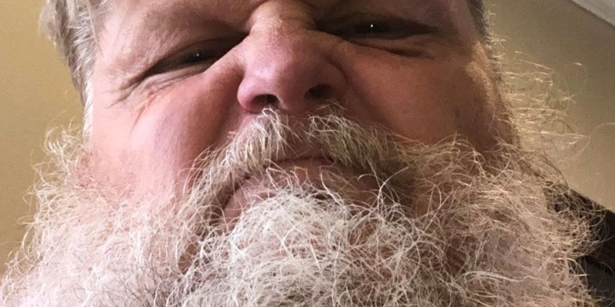 Close-up of a man's face with a full white beard.