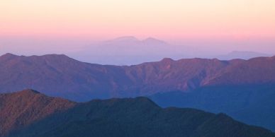 Sunset casts a pink glow over layered mountain ridges.
