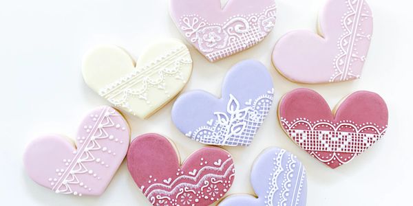 Intricate lace detail piped with royal icing onto delicious and colorful heart shaped sugar cookies 