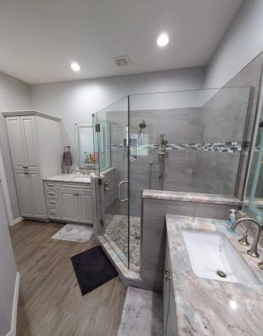 Modern bathroom with glass shower and marble countertops.
