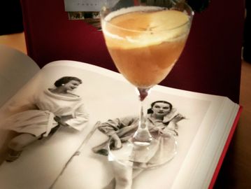 Cocktail glass on an open book with black-and-white photos.