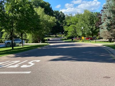 A suburban street with trees and parked cars.