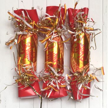 Three decorative Chinese firecracker ornaments with red, gold, and white accents.