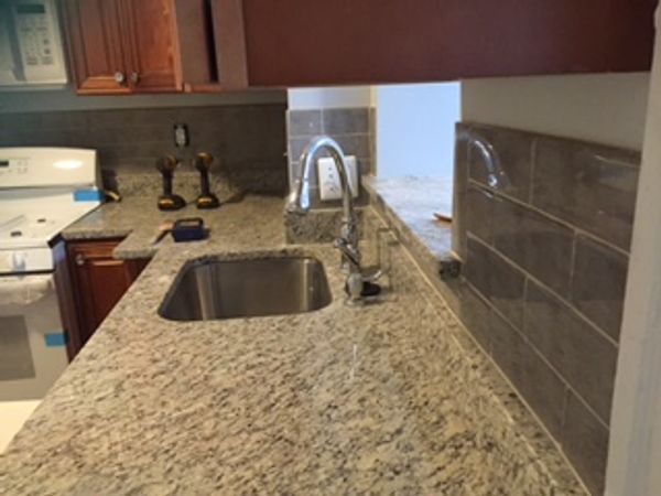 Modern kitchen granite countertop with stainless steel sink and chrome faucet.
