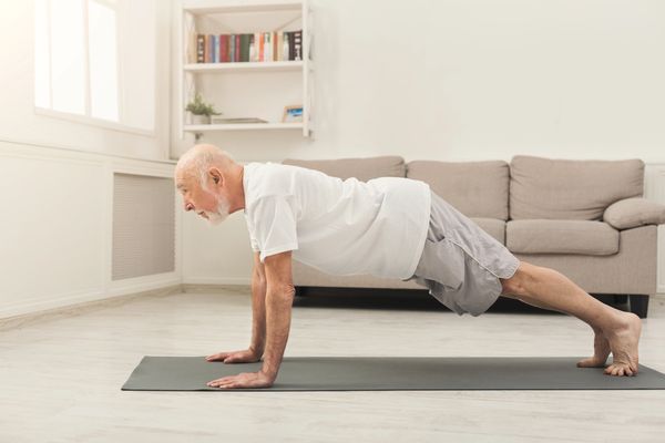 Senior virtually working out on yoga mat from home.