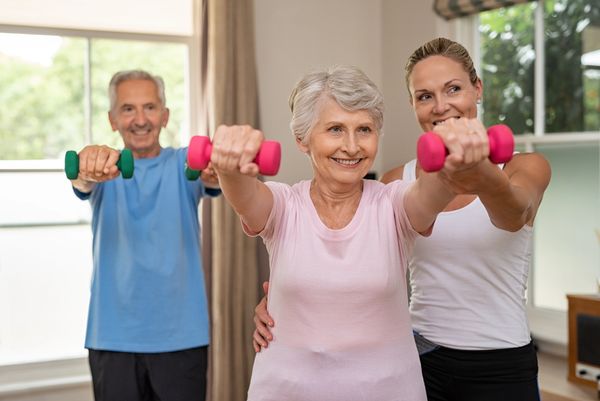 Personal trainer helping seniors with dumbbell exercise.
