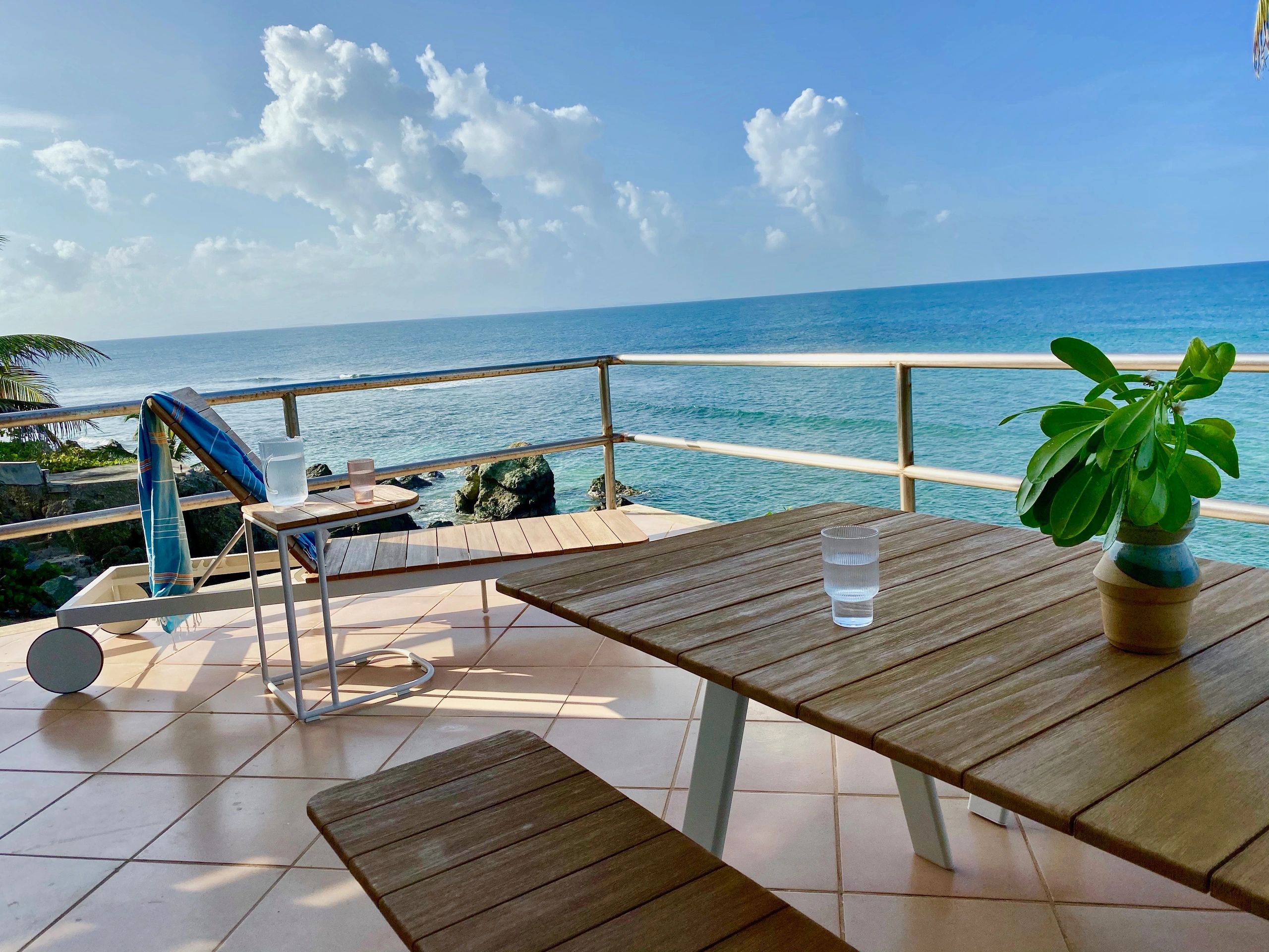 oceanfront deck with Caribbean views, lounge chair and outdoor dining table and bench