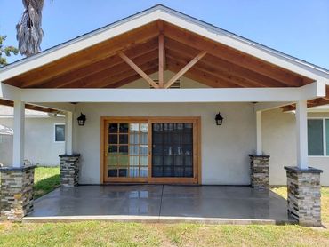 Home addition roof patio with wood ceiling planks, seamless roof extension & smooth concrete floor.