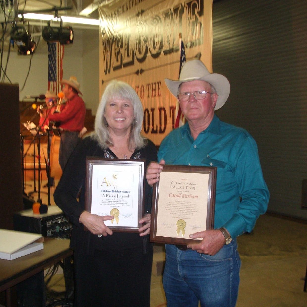 Two people holding framed awards at a country-themed event.