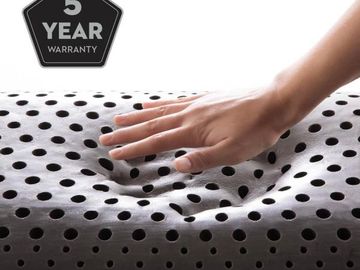 A hand presses into a soft, cushy, ventilated foam pillow featuring 5 year warranty.