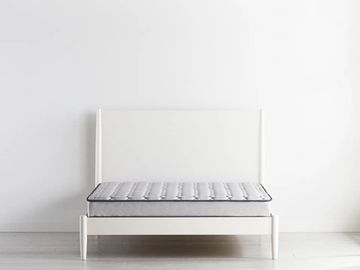 A small mattress and bed frame in a light, white room. 