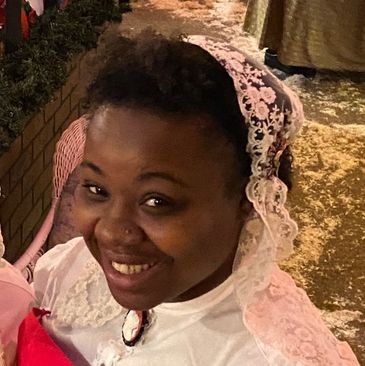 Smiling woman wearing a white lace veil and vintage attire.