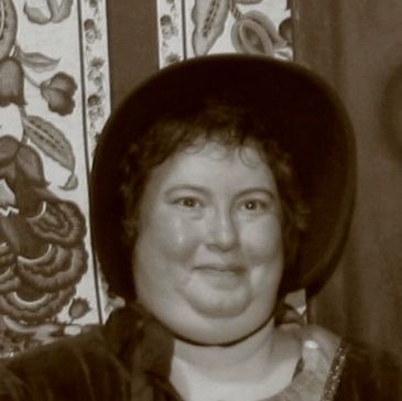 A person wearing a vintage hat and costume smiles softly.