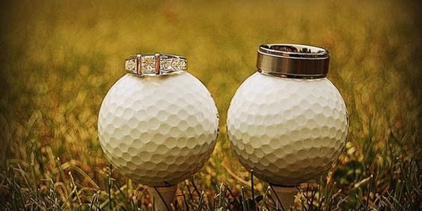 Wedding rings on top of two golf balls