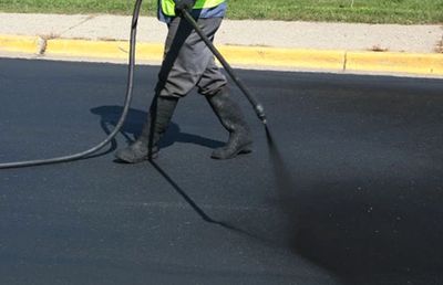 Seal coating sealer being applied to asphalt parking lot