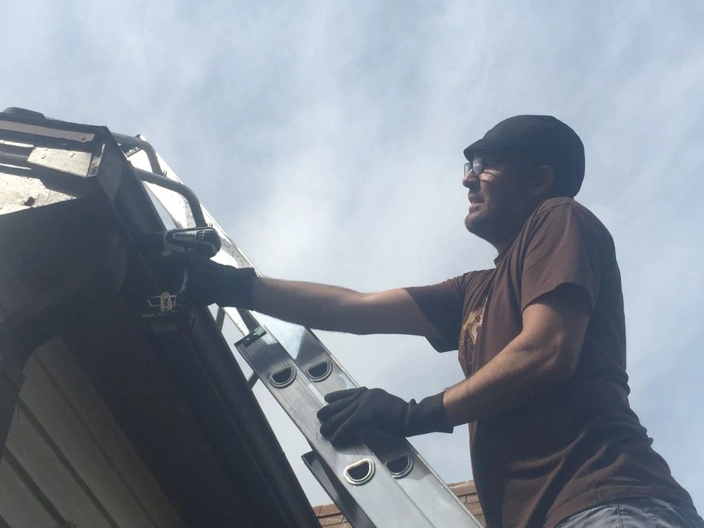 Timothy Austin working on gutter and Fascia board on a ladder