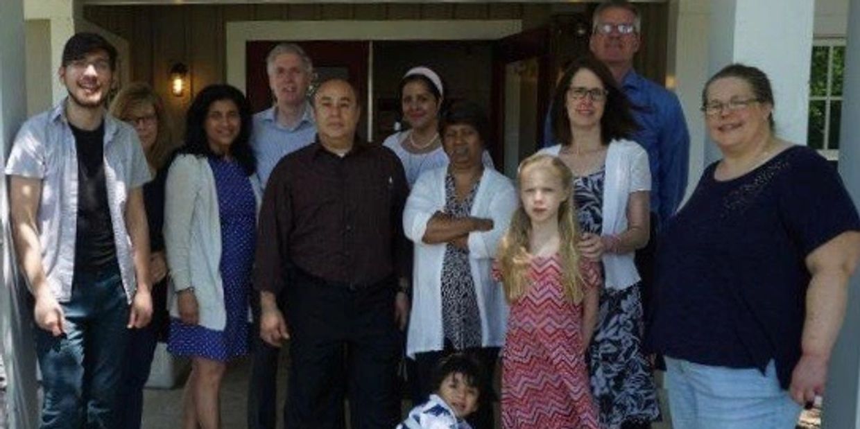 A diverse group of people posing outside a building on a sunny day.