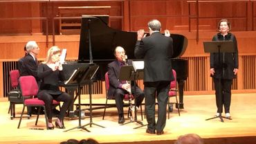 Musical ensemble performing on stage with piano, clarinet, and vocalist.