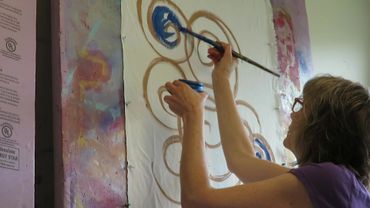 Chillon Leach paints artwork on a church textile called an altar parament.