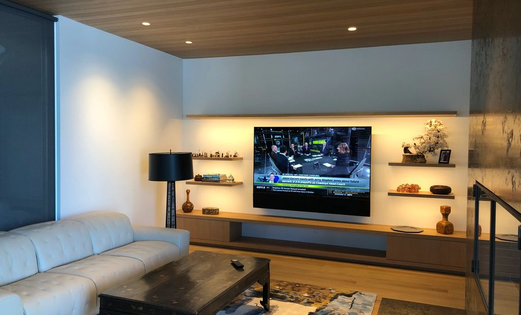 living room with a large TV, custom soundbar, lighting layers and a Control4 system controller.