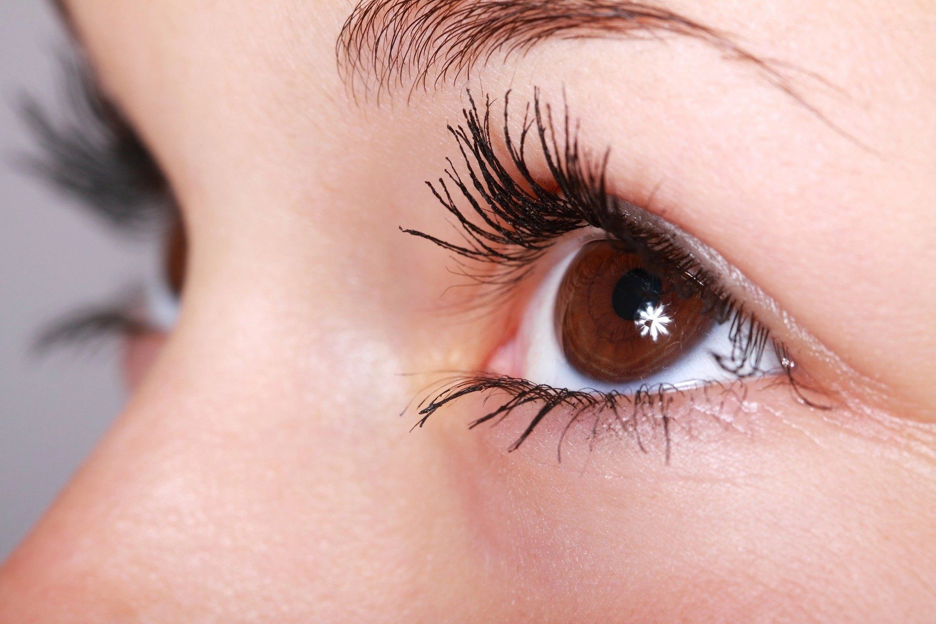 A close up shot of a lady with brown eyes and long eyelashes, looking up and away from the camera  