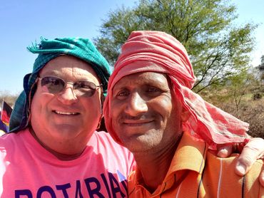 Two men smiling, wearing colorful headscarves outdoors.