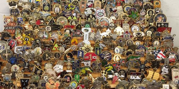 An assortment of challenge coins on a wooden rack.