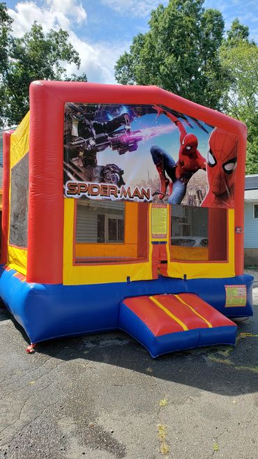 Colorful Spider-Man themed bounce house outdoors on a sunny day.