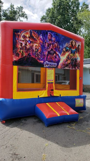 Colorful Avengers-themed inflatable bounce house outdoors on a sunny day.