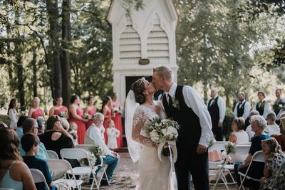 Bride and groom kissing leaving ceremony  in font of the steeple at Forest Hill Park