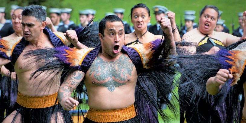 A group performing a traditional Maori haka dance with intense expressions.