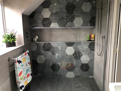 A stunning bathroom installation, including stylish, modern tiling and a wet room.