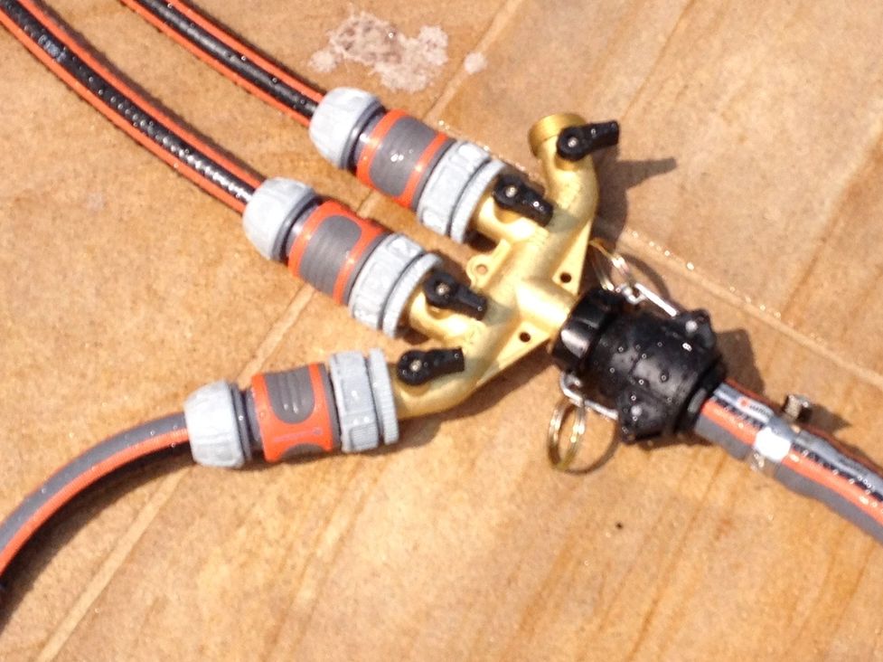 Garden hose splitter with three outlets on a tiled floor.