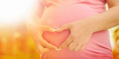 Pregnant women hands forming heart over belly