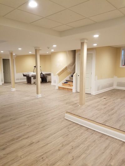 finished basement with vinyl plank flooring and wood columns