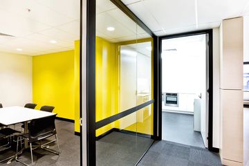 aluminium framed glass office partition with bright yellow wall in a modern office