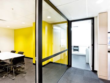 aluminium framed glass office partition with bright yellow wall in a modern office