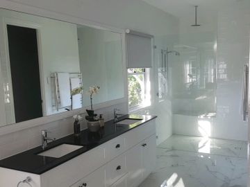 modern bathroom with frameless glass shower panel  large framed wall mirror