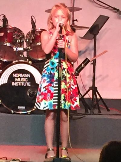 Girl singing a song on the Norman Music Institutes Performance stage