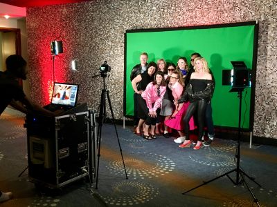 Group photo in front of a green screen with camera setup.
