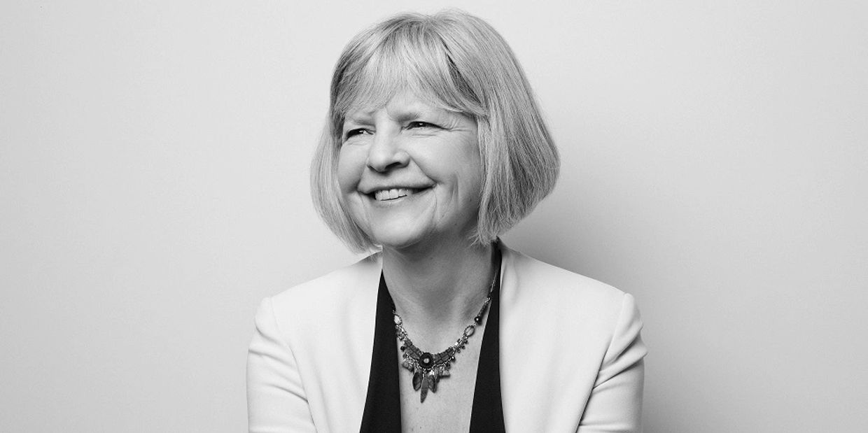 Black and white image of Fiona Crean smiling against a grey background.  