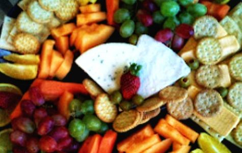 An elegant display of diffedifferent cheeses and a variety  of fresh, tasty fruit, as well as crcrac
