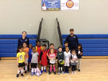 A group of children with two coaches in a gymnasium.