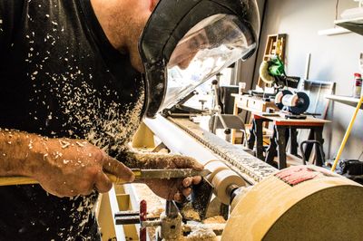 man making a custom hospitality contract furniture table leg on a lathe